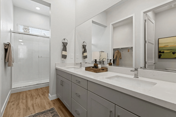 A bathroom with a white sink, a mirror, and a glass shower door.